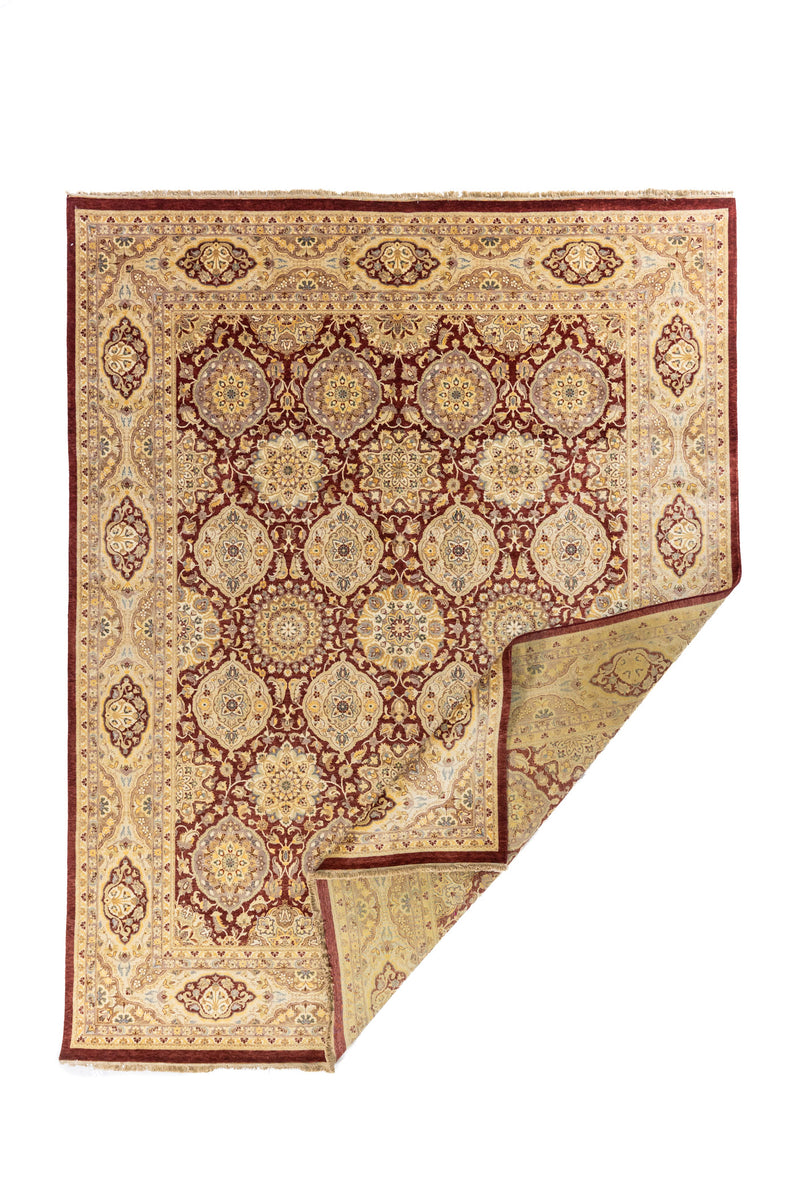 Alfombra oriental roja y beige con esquina doblada, mostrando el reverso y el detalle de tejido artesanal.