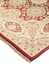 Primer plano de esquina de alfombra tradicional con diseño floral en tonos beige, rojo vino y detalles azul suave.