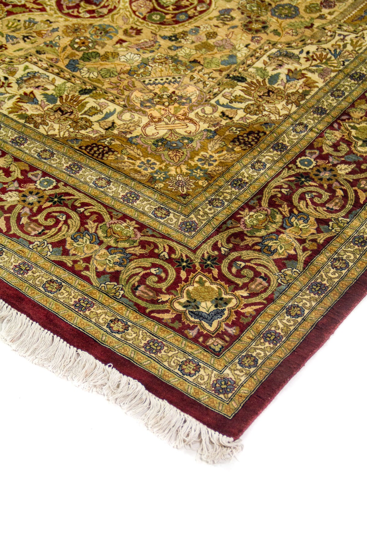 Detalle de esquina de alfombra persa con borde rojo y patrones florales ornamentales en tonos beige, azul y dorado.