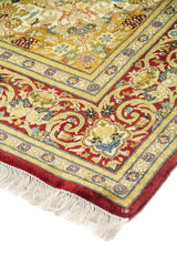 Detalle del borde y esquina de una alfombra oriental con patrones florales y guarda decorativa roja.
