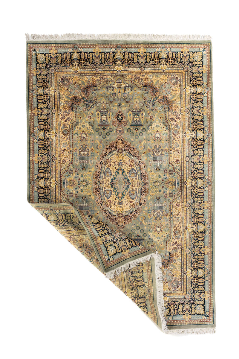 Alfombra ornamental en tonos suaves con una esquina doblada que muestra el reverso y el acabado con flecos