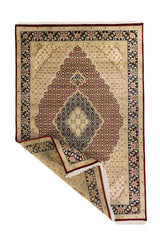 Alfombra oriental tradicional con una esquina doblada que permite ver el reverso, el grosor del tejido y los flecos en tono blanco suave.