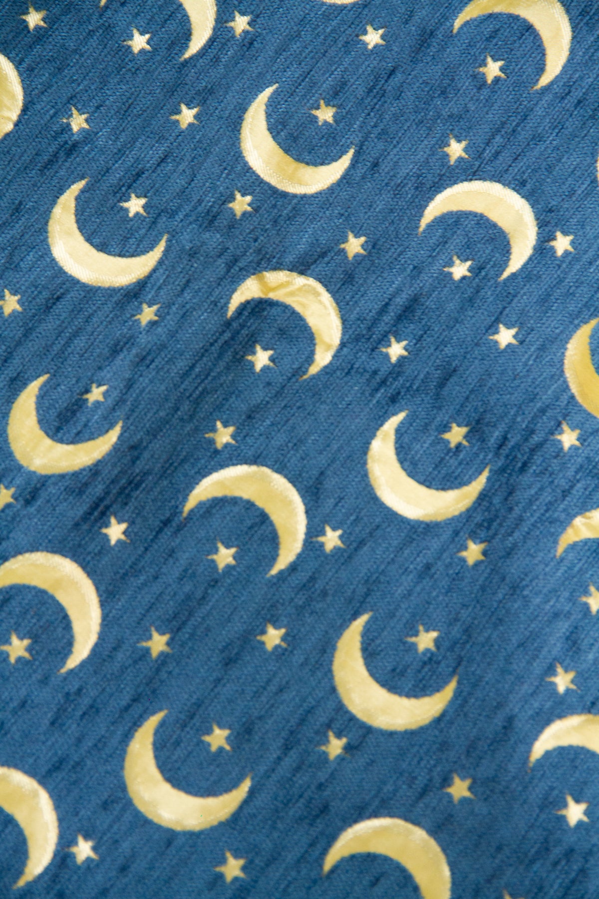 Detalle de textura de tela para almohadón celeste con lunas y estrellas doradas