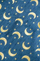 Detalle de textura de tela para almohadón celeste con lunas y estrellas doradas