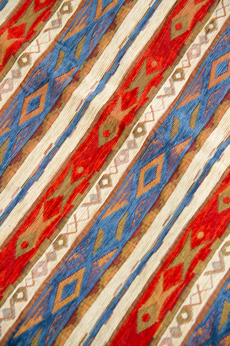 Detalle de textura de tela para almohadón Kayseri con rayas y diseño geométrico en azul y rojo