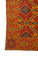 Detalle del diseño geométrico con rombos y motivos florales en textil dorado y bordó