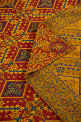 Detalle del reverso dorado y frente bordó del textil decorativo con motivos geométricos