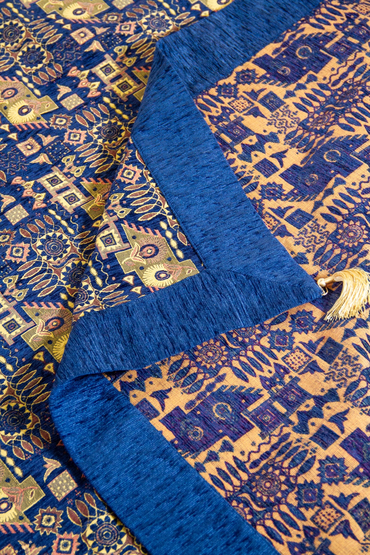 Detalle del reverso y frente del textil Kaisery Azul con motivos geométricos en tonos dorados