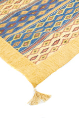 Detalle de textura del textil Kayseri beige con guarda dorada y fleco decorativo