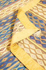 Detalle del reverso y flecos del textil decorativo beige con motivos geométricos