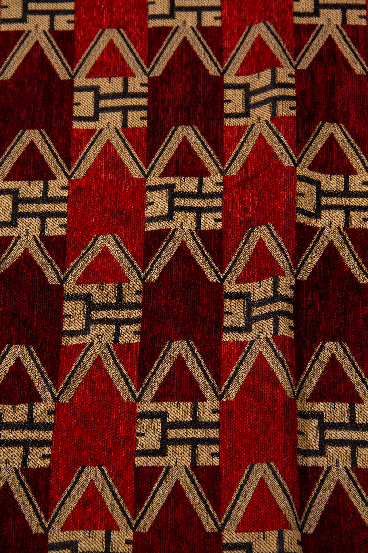 Detalle del diseño geométrico del textil bordó con figuras en V, triángulos y tonos rojos