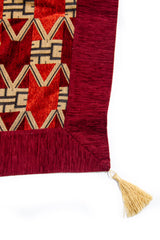 Detalle de textura y borde bordó del textil decorativo con fleco en la esquina