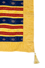 Detalle de textura del textil decorativo amarillo con guarda roja, rayas azules y fleco en la esquina