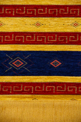 Detalle del diseño geométrico con rombos, guardas rojas y rayas azules sobre textil amarillo