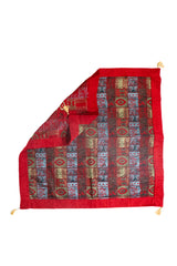 Textil decorativo rojo con diseño patchwork y reverso visible en formato cuadrado
