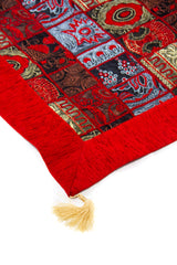 Detalle de textura del textil Kayseri rojo con diseño patchwork y fleco decorativo.