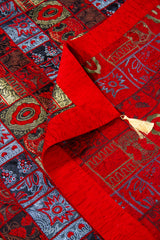 Detalle del reverso y guarda del textil decorativo rojo con diseño geométrico y fleco.