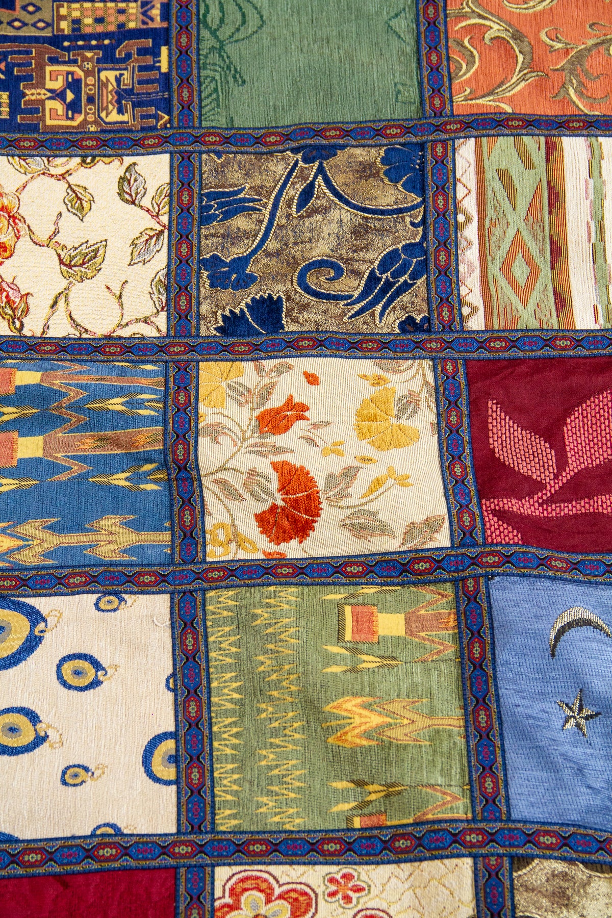 Detalle del diseño patchwork con motivos florales, geométricos y guarda azul en textil multicolor