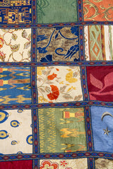 Detalle del diseño patchwork con motivos florales, geométricos y guarda azul en textil multicolor