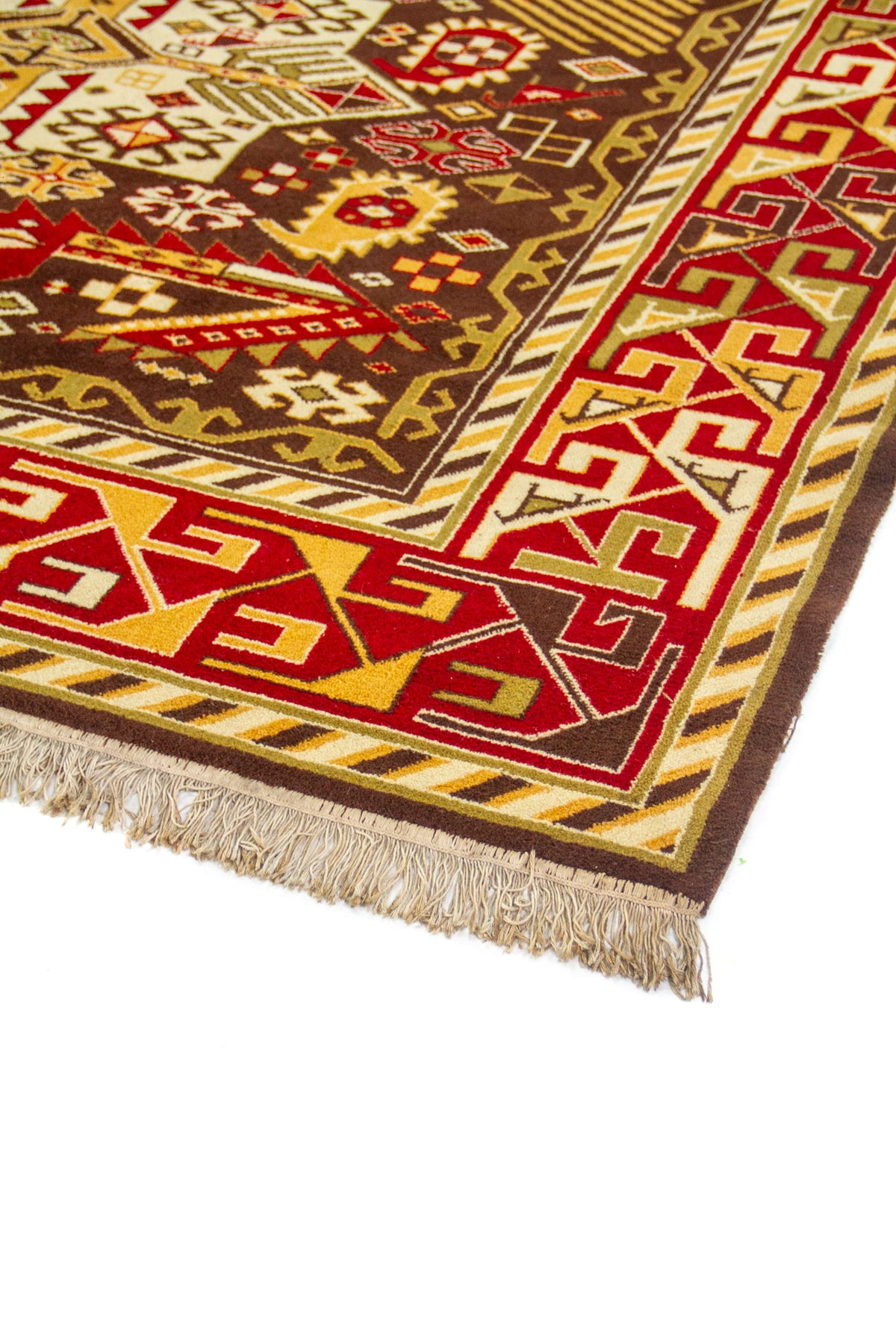 Vista lateral en perspectiva de la alfombra mostrando el marco geométrico rojo y el campo central marrón con motivos simétricos.