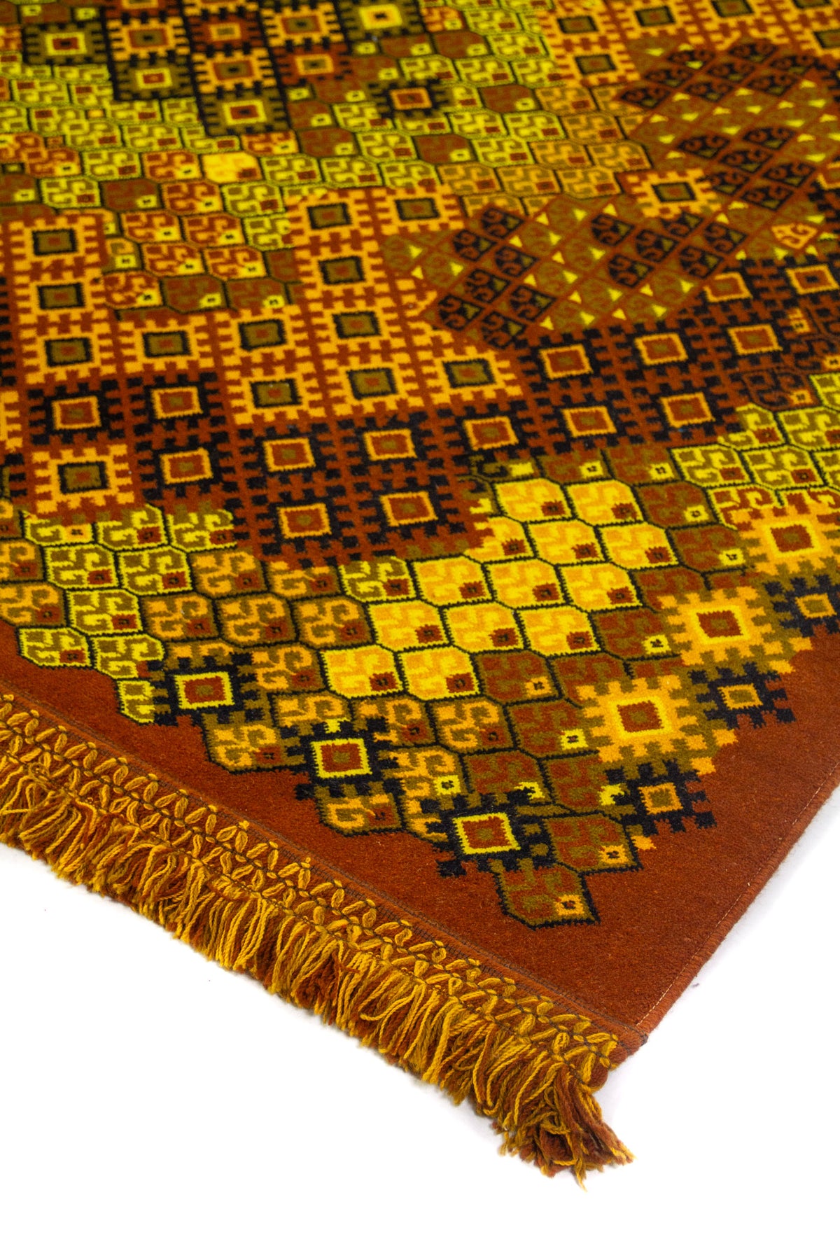 Detalle de esquina de alfombra con patrón geométrico tribal en tonos amarillo, rojo y marrón