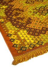 Primer plano de alfombra artesanal con motivos geométricos repetitivos en colores amarillo, rojo y marrón