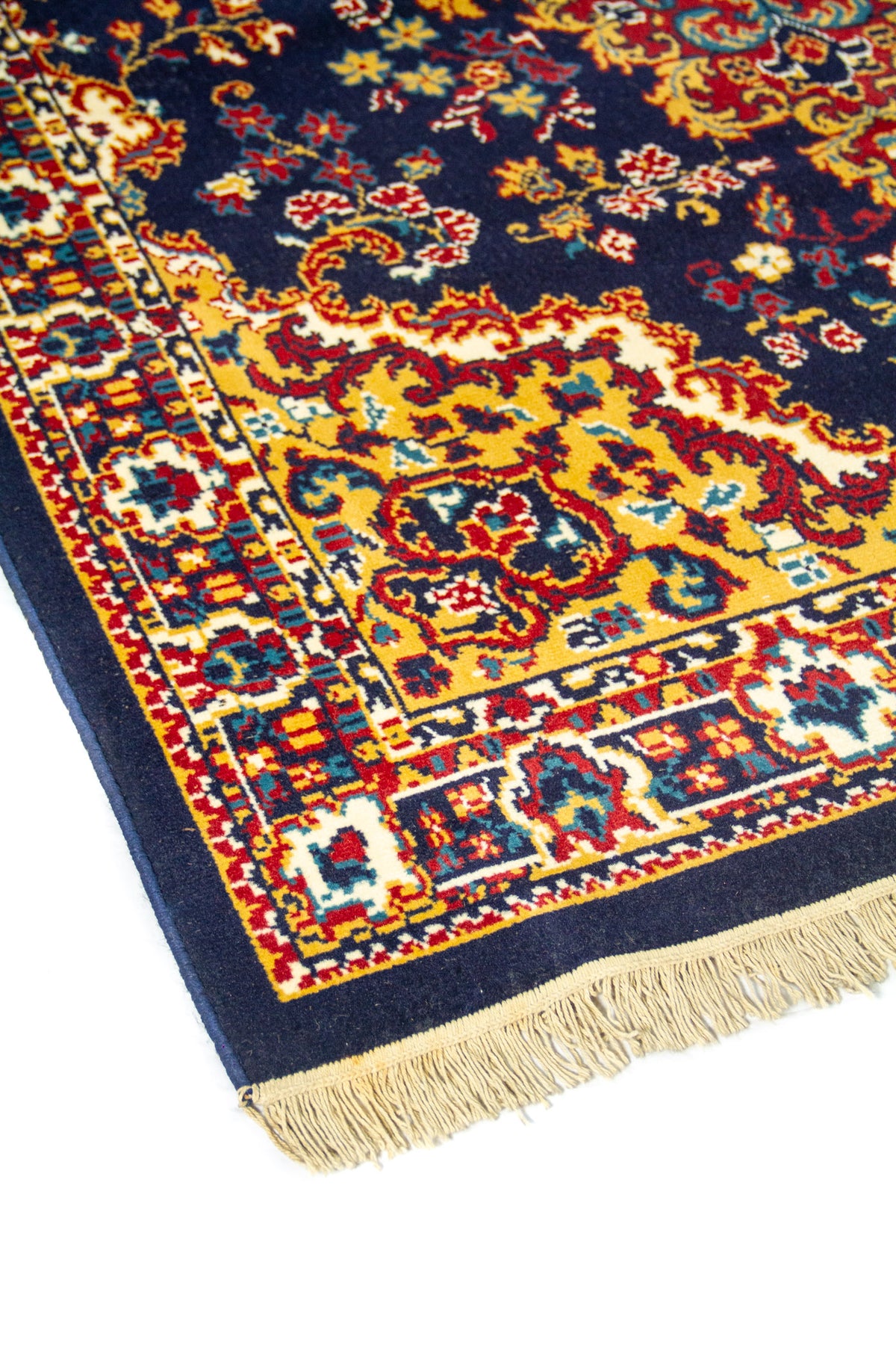 Primer plano de borde de alfombra oriental con diseño geométrico y floral en tonos azul, rojo, dorado y blanco.