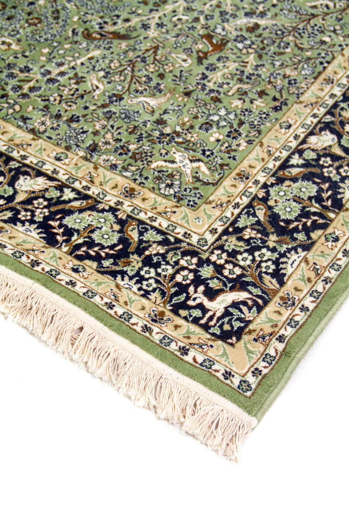 Detalle de esquina de alfombra verde con guarda azul floral, borde beige y flecos claros