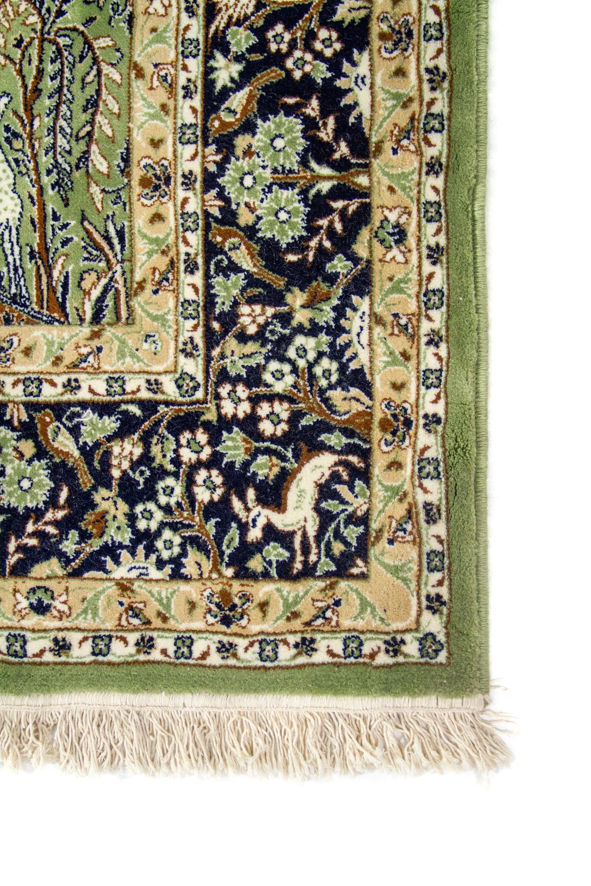 Primer plano de borde de alfombra verde con cenefa azul floral y acabado artesanal con flecos
