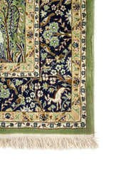 Primer plano de borde de alfombra verde con cenefa azul floral y acabado artesanal con flecos