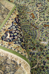 Alfombra verde doblada en detalle con patrón floral, figuras animales y textura visible