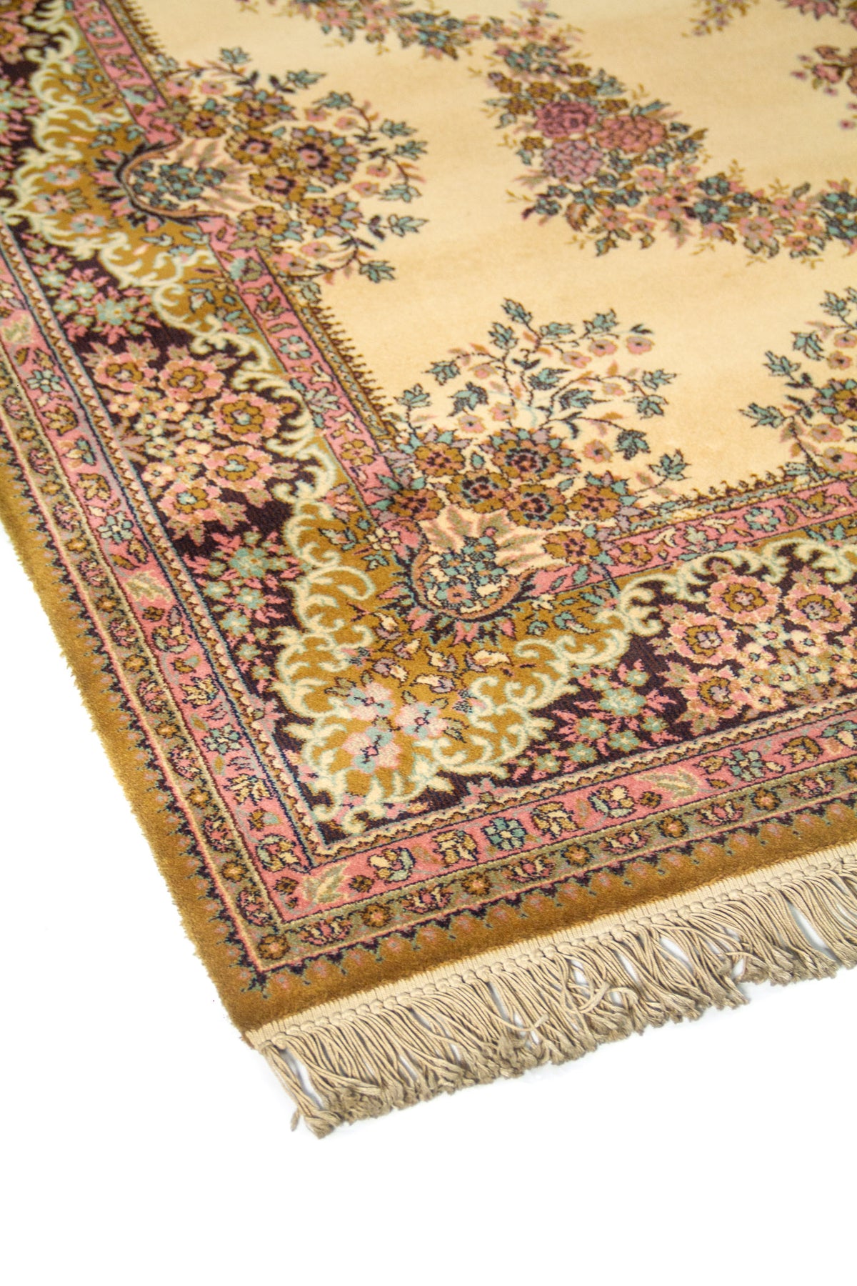 Vista en ángulo de alfombra oriental con centro beige, ramilletes florales simétricos y guarda decorativa en tonos rosa y dorado.
