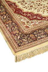 Primer plano de alfombra ornamental con centro beige, formas curvas en rojo y guarda floral oscura de gran detalle.