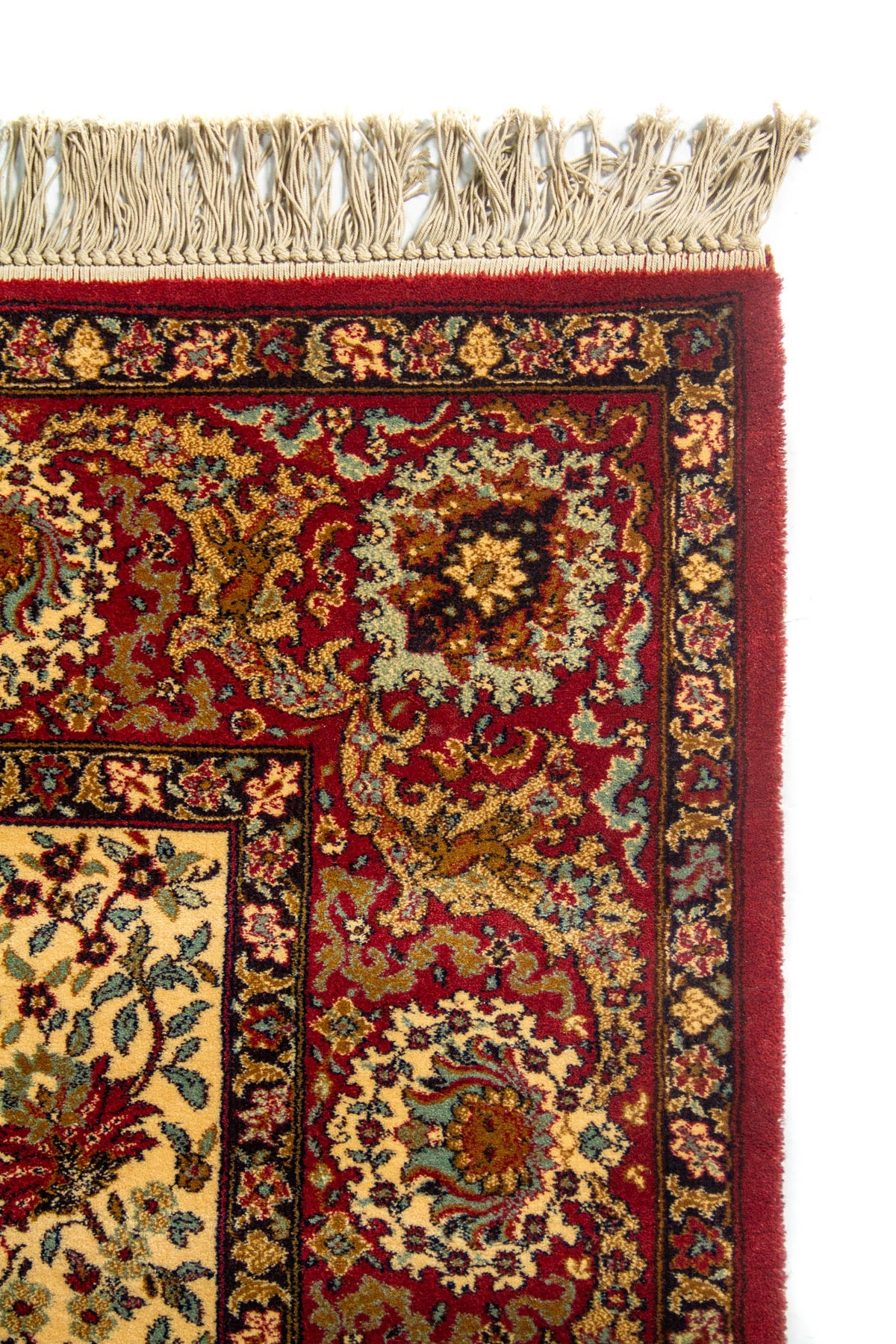 Detalle superior de alfombra clásica con flecos claros, borde rojo intenso y patrones ornamentales de inspiración oriental.