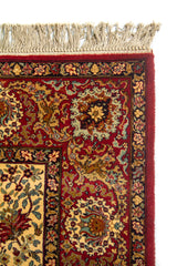 Detalle superior de alfombra clásica con flecos claros, borde rojo intenso y patrones ornamentales de inspiración oriental.