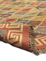 Alfombra kilim tradicional con patrón geométrico en colores cálidos, mostrando detalles de flecos y bordes en tonos rojizos