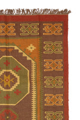 Detalle de una alfombra artesanal de lana con diseño geométrico tribal en tonos tierra y óxido.