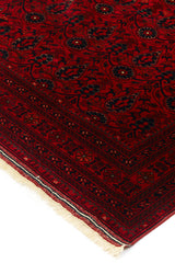 Alfombra persa y oriental con un diseño elegante de medallón central en tonos rojos y azules, colocada en un espacio decorado con muebles clásicos.