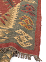 Alfombra artesanal de lana con diseño geométrico tribal en tonos cálidos y terrosos.