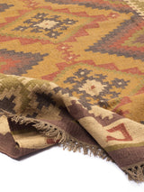 Alfombra kilim con diseño geométrico en tonos tierra y detalles de flecos.
