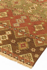 Alfombra kilim con diseño de mosaicos geométricos en tonos marrones, rojizos y beige, con detalles de flecos en el borde.