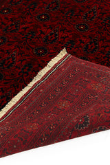 Alfombra persa y oriental con un diseño elegante de medallón central en tonos rojos y azules, colocada en un espacio decorado con muebles clásicos.