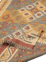 Alfombra rectangular de lana con patrón étnico y flecos. Tonos cálidos y textura natural, ideal para espacios acogedores.