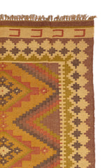 Alfombra kilim con diseño geométrico en tonos tierra y detalles de flecos.