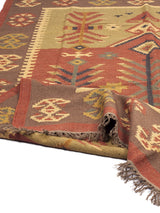 Alfombra Kilim Verde Rojo de Kerestegian con diseño geométrico tribal en tonos verdes, rojos y marrones, con motivos de rombos y líneas entrelazadas.