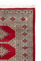 Alfombra persa y oriental con un diseño geométrico clásico en tonos terrosos, desplegada en un espacio interior.