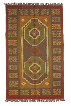 Detalle de una alfombra artesanal de lana con diseño geométrico tribal en tonos tierra y óxido.