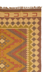 Detalle de una alfombra artesanal de lana con diseño geométrico tribal en tonos tierra y óxido. Motivos naturales y textura rústica.