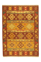 Alfombra kilim con motivos geométricos en tonos marrones, dorados y naranjas, con borde de flecos y detalles intrincados.