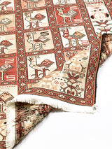  Alfombra oriental con diseño geométrico y motivos de aves. Colores cálidos y textura densa.